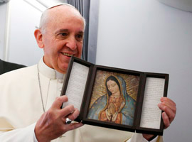 Pope Francis holds an image of Our Lady of Guadalupe after receiving it as a gift from a journalist aboard the papal flight to Brazil. (CNS photo/Paul Haring)
