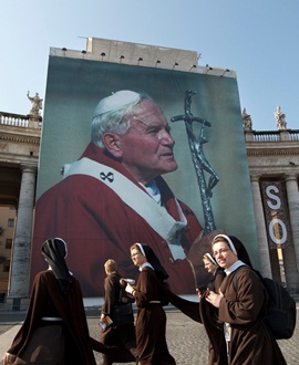 A group of nuns walks by a huge image of Blessed John Paull II displayed in St. Peter's Square at his beatification ceremony on May 1, 2011. CNS Photo/Paul Haring.