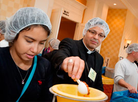 Local volunteer Paola Correa and Auxiliary Bishop Alberto Rojas of Chicago join in a service project before the November meeting. CNS Photo/Nancy Phelan Weichec.