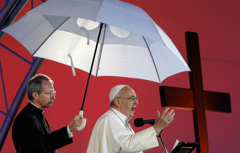 Msgr. Guido Marini, papal master of ceremonies, holds an umbrella for Pope Francis as he addresses World Youth Day Pilgrim. (CNS photo/Paul Haring)