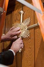A worker places a gold cross on the Holy Door at the Basilica of the National Shrine of the Immaculate Conception in Washington, DC.  CNS photo/Matthew Barrick