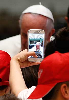 A youth takes a photo on a cell phone as Pope Francis meets children of Italian prisoners in Paul VI hall at the Vatican. CNS photo/Paul Haring