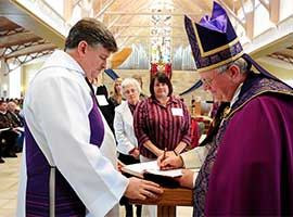 Bishop David L. Ricken of Green Bay, Wis., signs the Book of Elect during the Rite of Election of catechumens and Call to Continuing Conversion of candidates at Our Lady of Lourdes Church in De Pere, Wis., in 2014. CNS photo/Sam Lucero, The Compass
