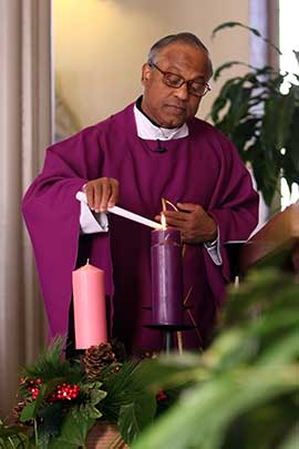Father Francis Lasrado lights a candle in an Advent wreath at Infant Jesus Church in Port Jefferson, N.Y., on the first day of Advent in 2015. CNS photo/Gregory A. Shemitz