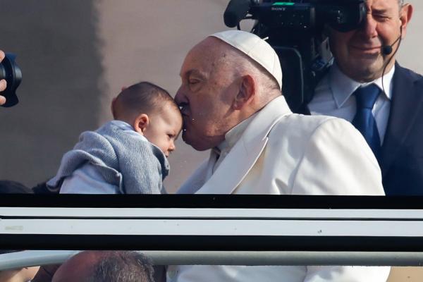 Pope Francis kisses a child on the head.