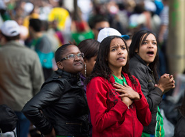 Pilgrims watching a Jumbotron react as they see Pope Francis getting out of his popemobile to hug a child in Rio de Janeiro. (CNS photo/Tyler Orsburn)