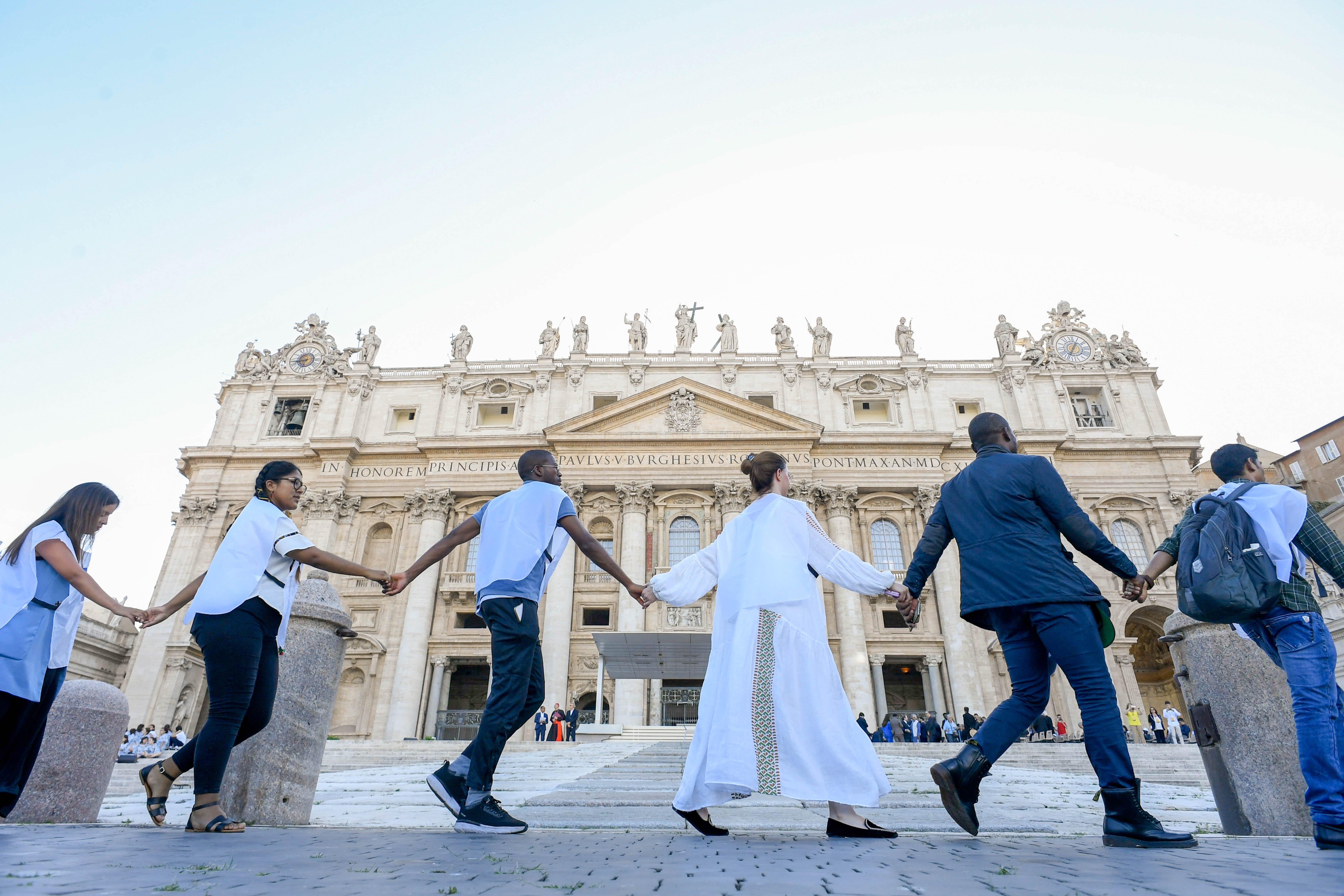 Young people hold hands in St. Peter's Square