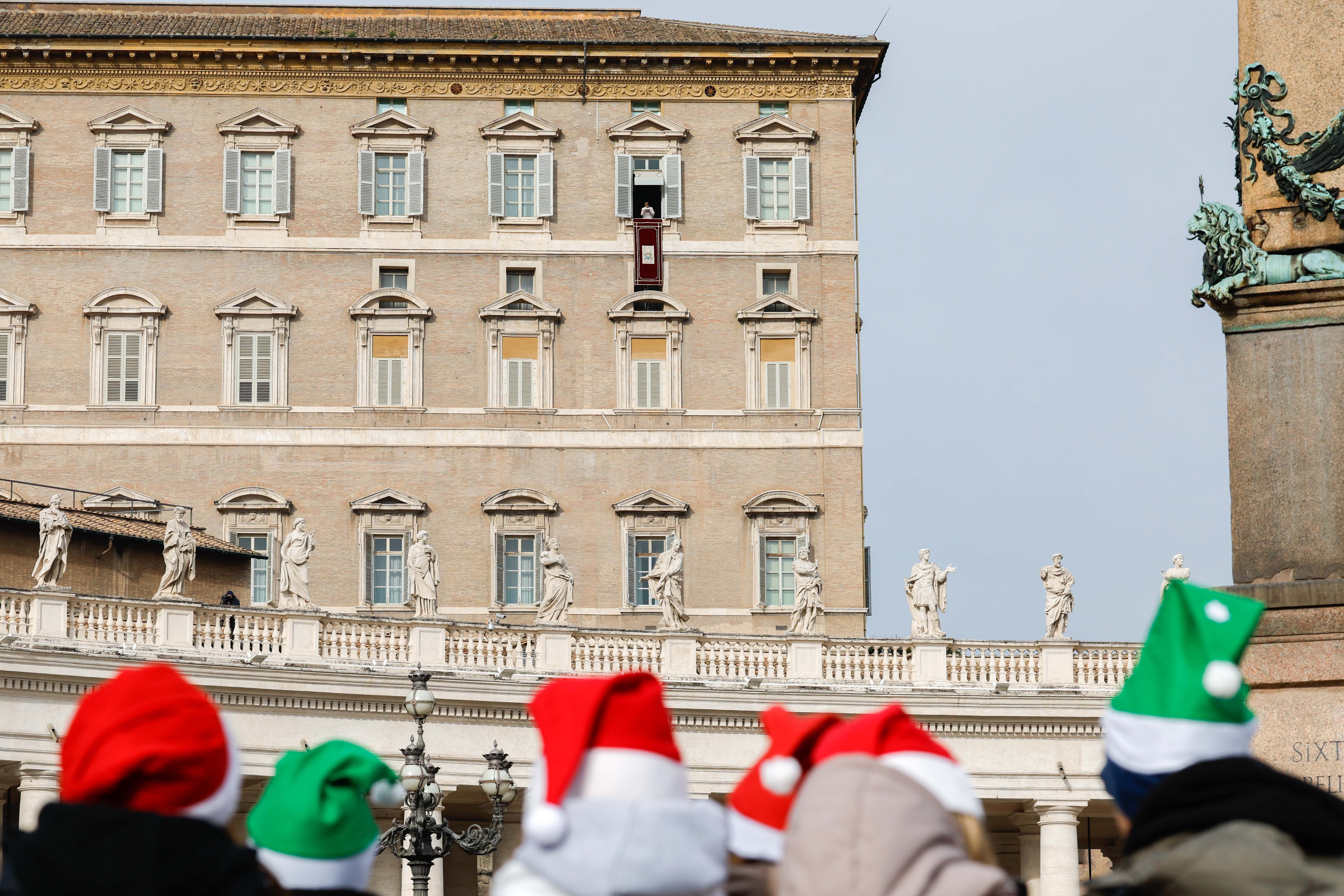 Visitors in St. Peter's Square wear Christmas hats.