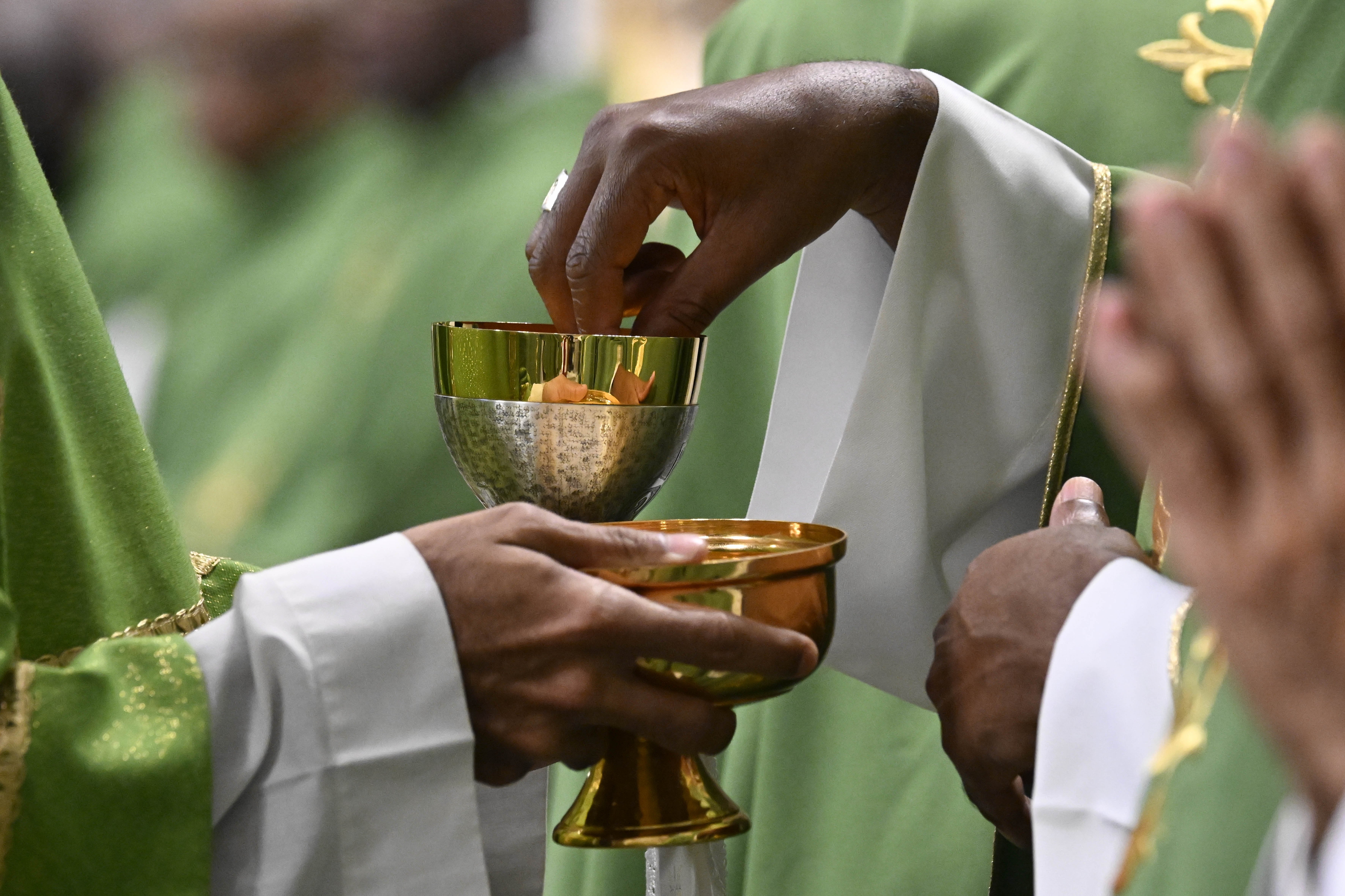 A concelebrating priest dips the host into consecrated wine during Mass.