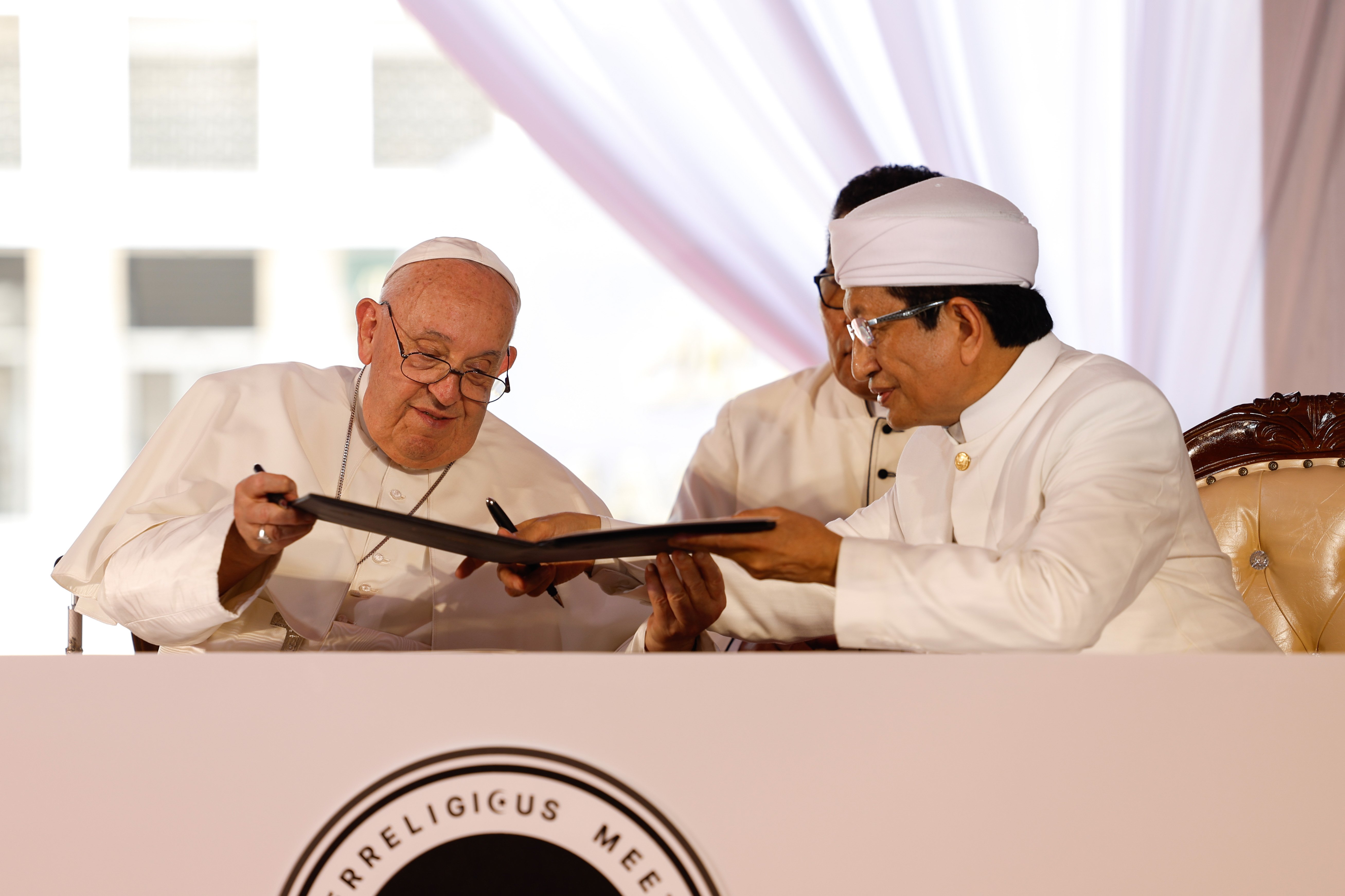 Pope Francis signs a document.