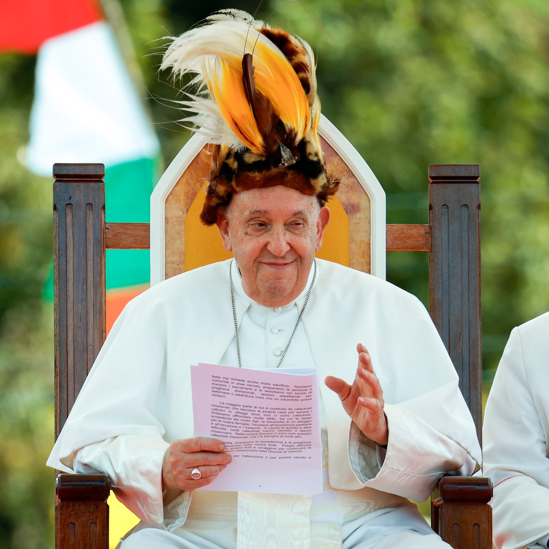 Pope Francis smiles while wearing a traditional Papua New Guinean headdress.