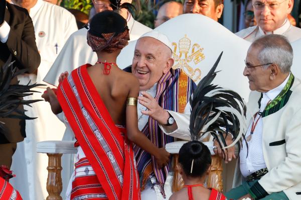 Pope Francis greets a child in traditional dress.