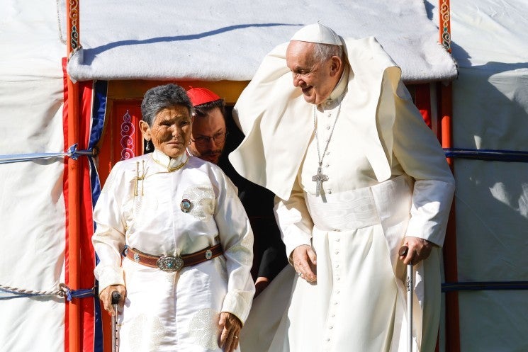 Pope Francis stands with a Mongolian woman outside a ger.