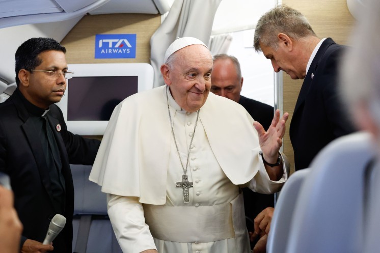 Pope Francis greets journalists aboard his flight to Rome. 
