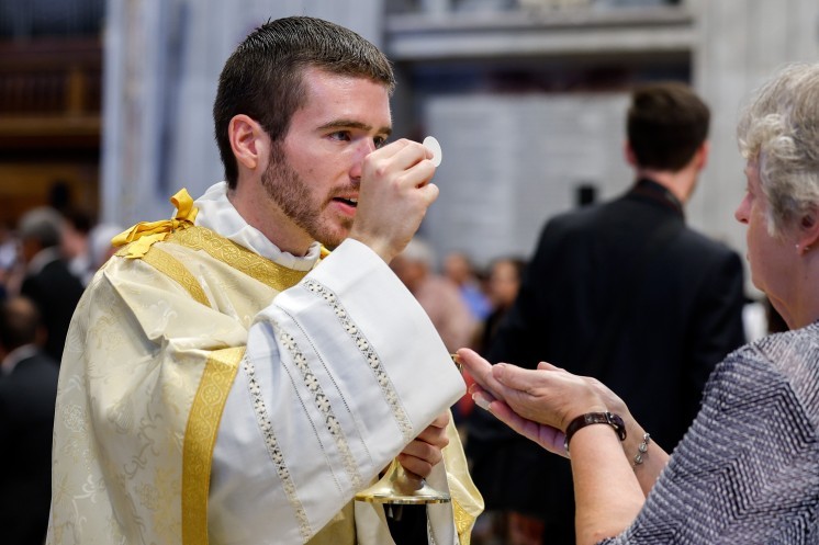 A newly ordained deacon distributes Communion.