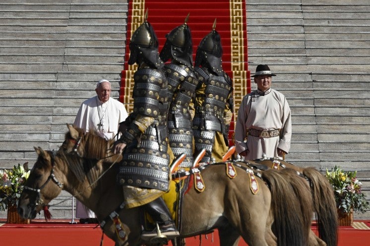 Members of a mounted honor guard, dressed in armor, ride past Pope Francis.