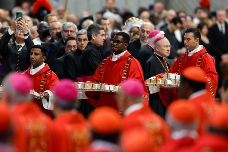 Deacons carry palliums.
